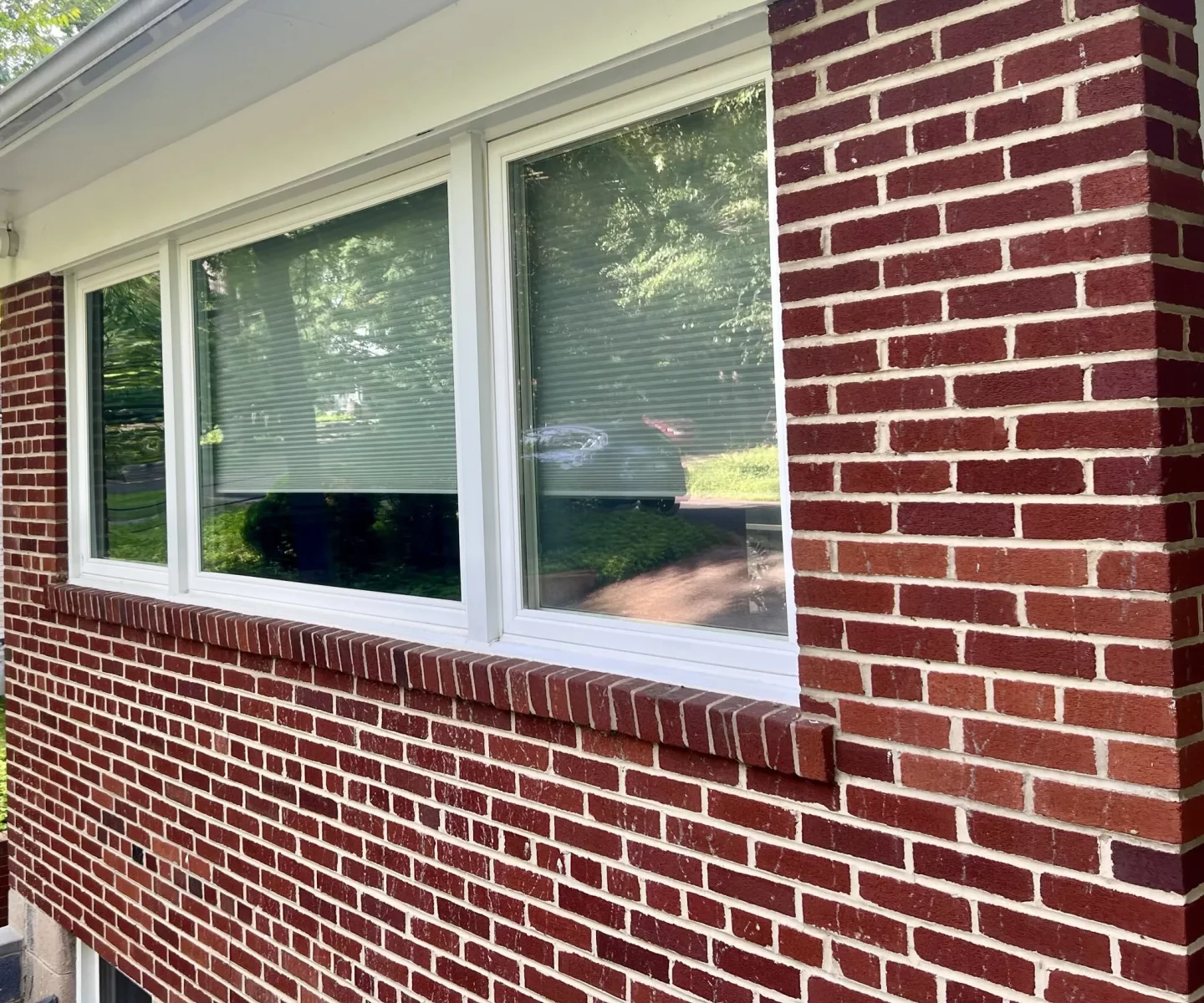Exterior view of a large window with white frame in a brick wall