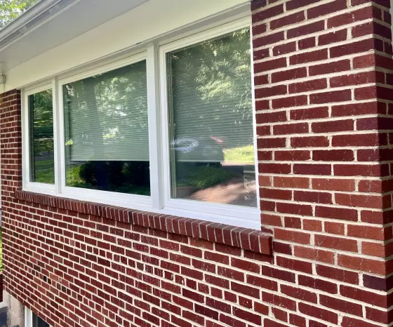 Exterior view of a large window with white frame in a brick wall