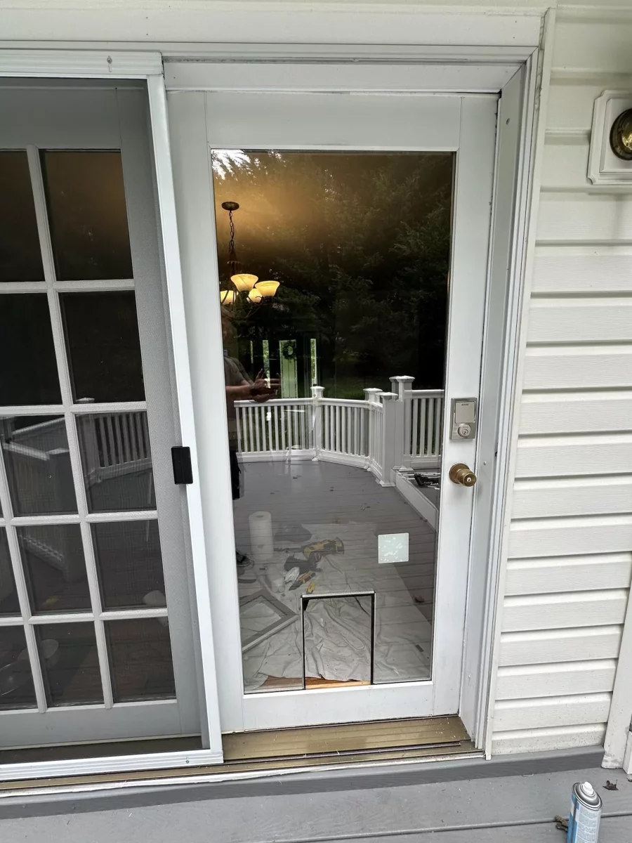 Glass door with pet door installation in progress and tools on deck