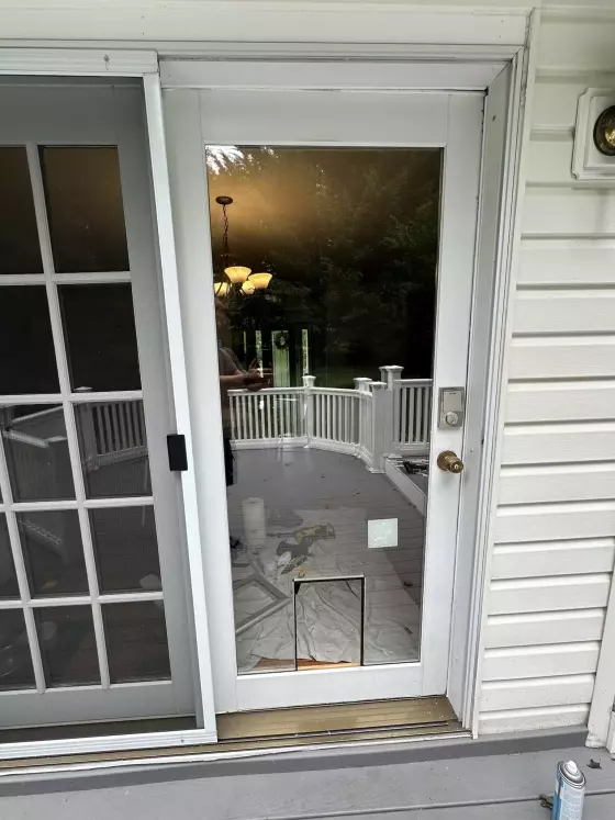 Glass door with pet door installation in progress and tools on deck