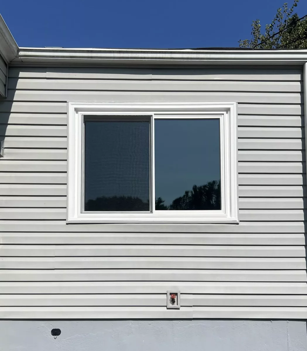 Exterior view of a sliding window installed in vinyl siding