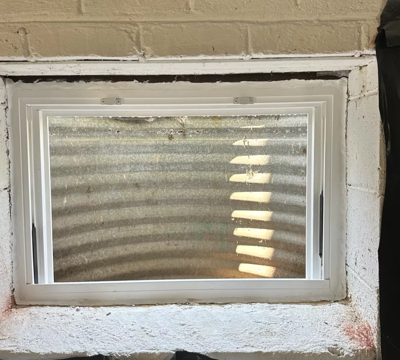 Basement window with white frame set in concrete wall