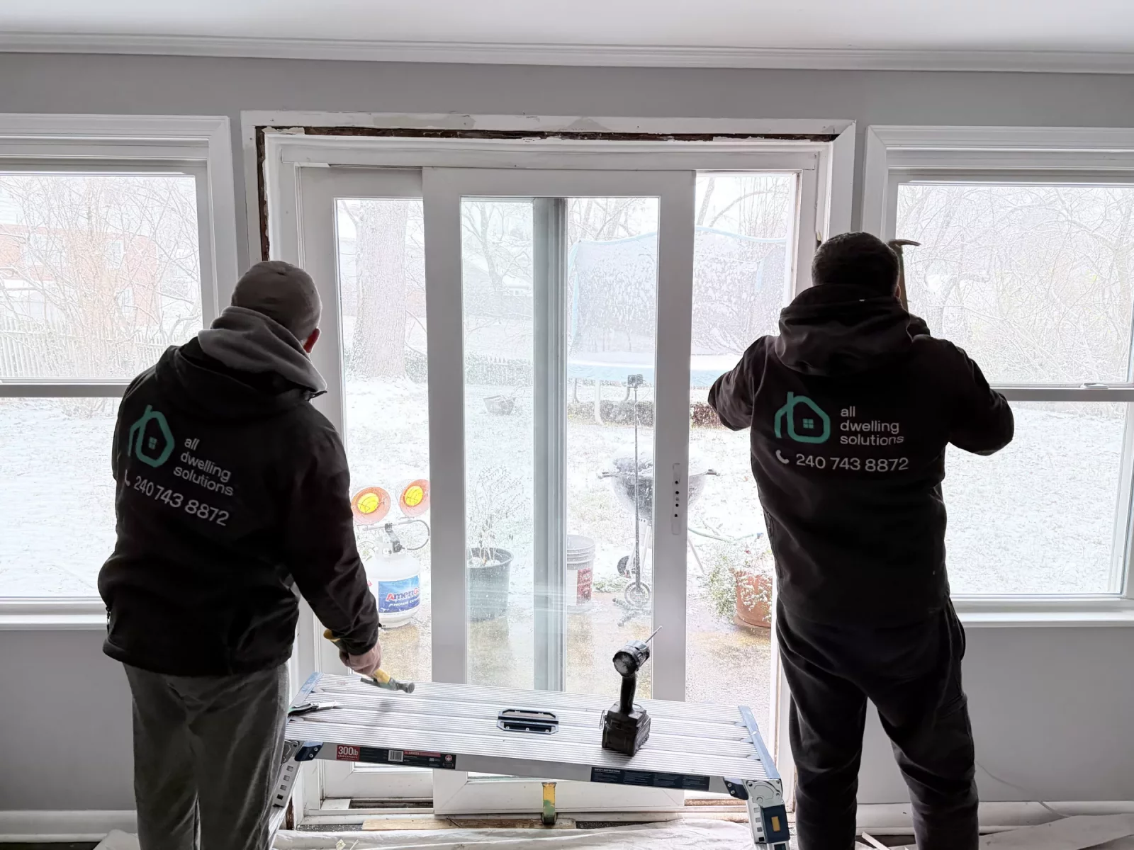 Two workers installing a sliding patio door inside a home