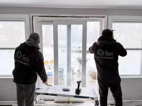 Two workers installing a sliding patio door inside a home