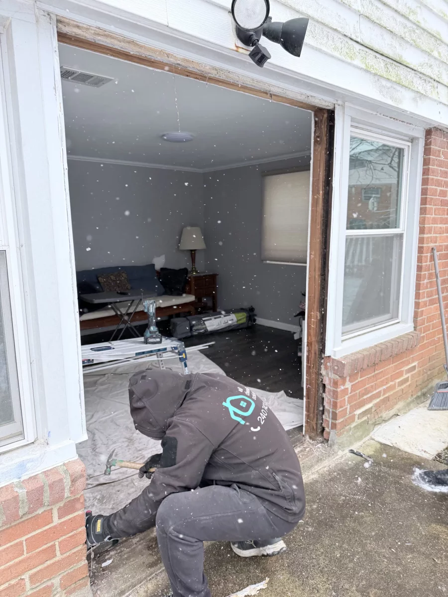 Person working on exterior door frame removal with tools visible