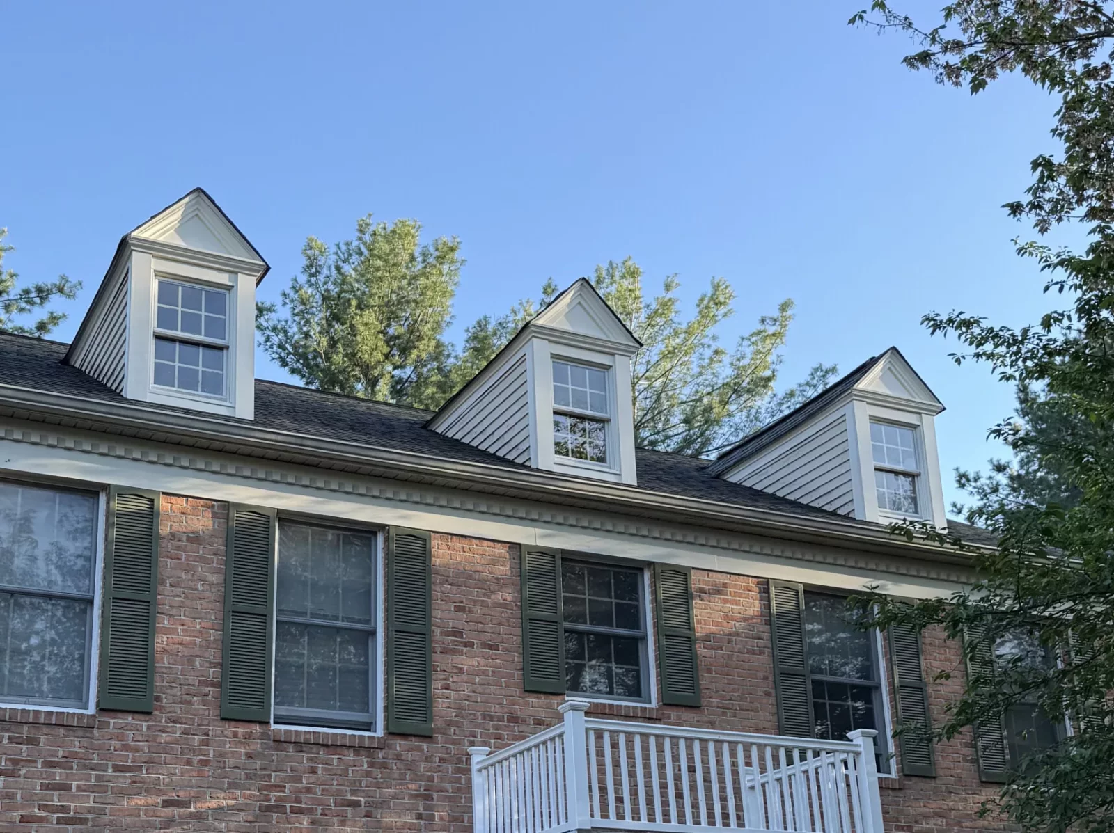 Front exterior of a brick house with multiple windows and shutters