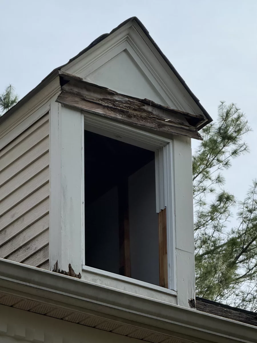 Exterior view of dormer with rotted wood trim and missing window