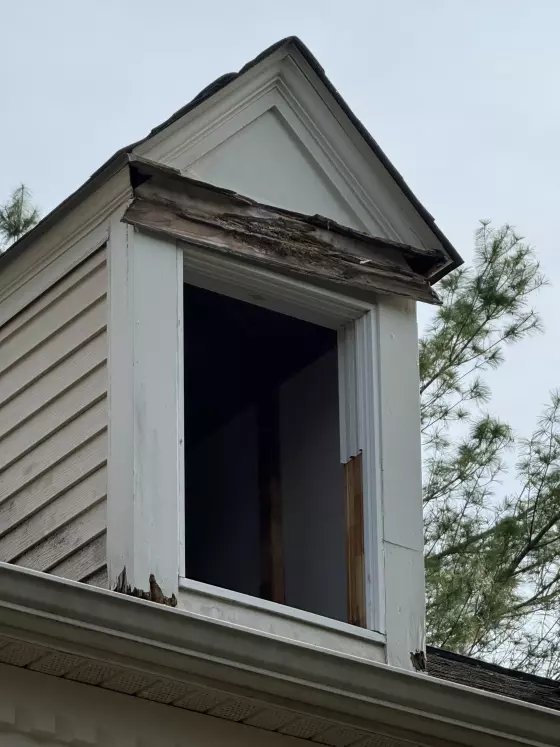 Exterior view of dormer with rotted wood trim and missing window