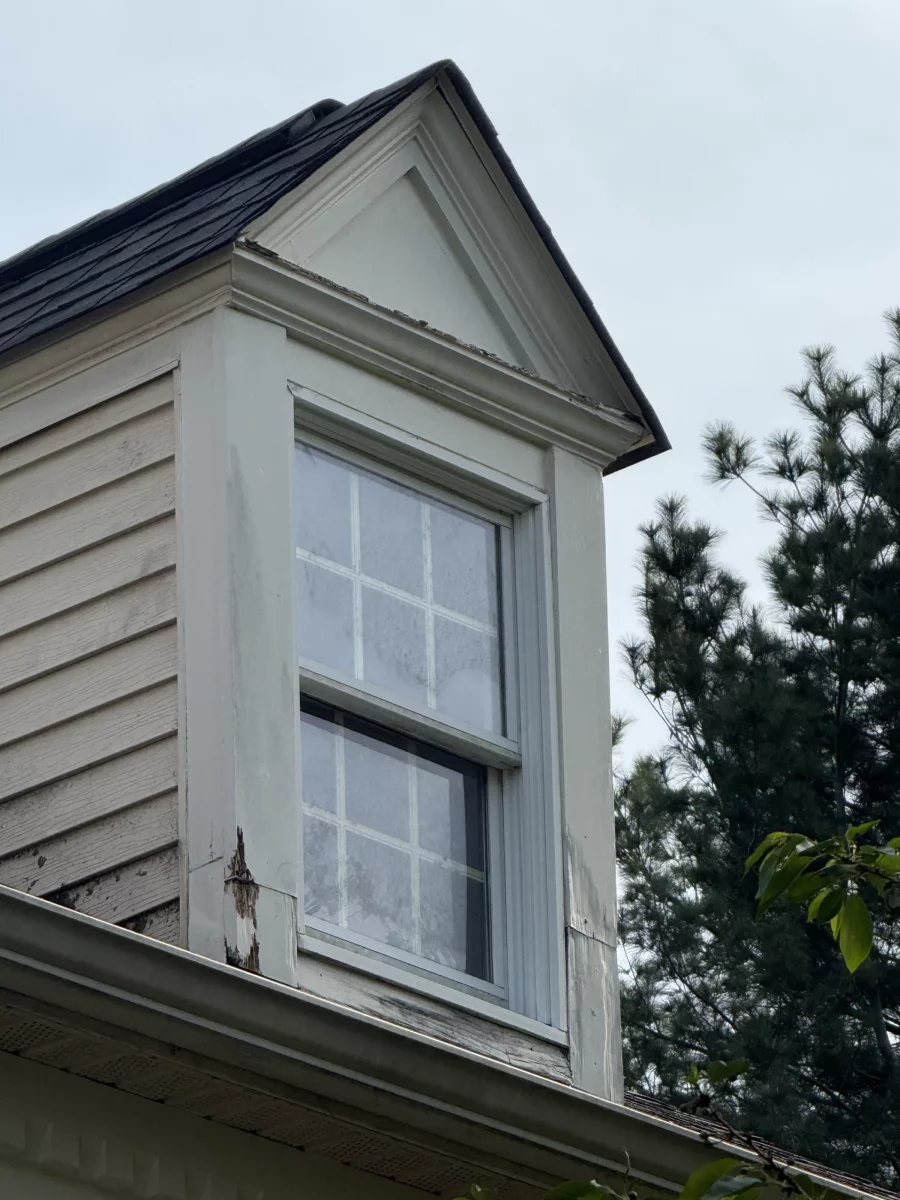 Exterior window with visible rot and damaged trim on residential building