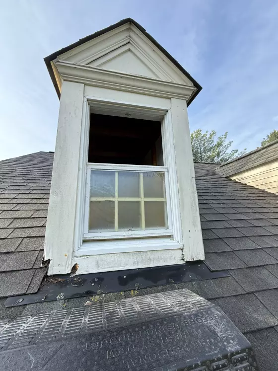 Exterior close-up of dormer window with visible wood rot and peeling trim