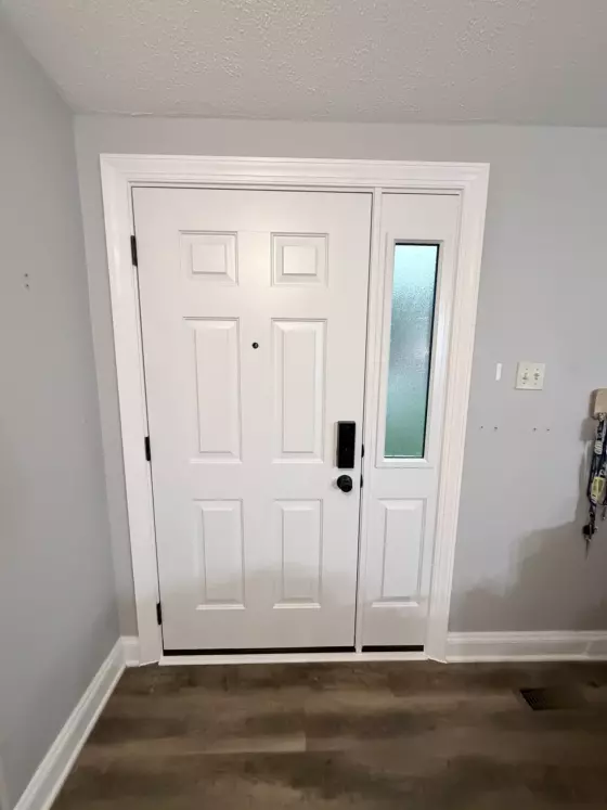 White entry door with glass sidelight and trim viewed from inside