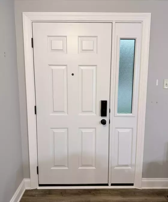 White entry door with glass sidelight and trim inside a home