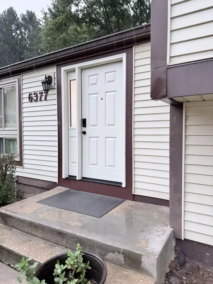 White entry door with side window on residential house exterior