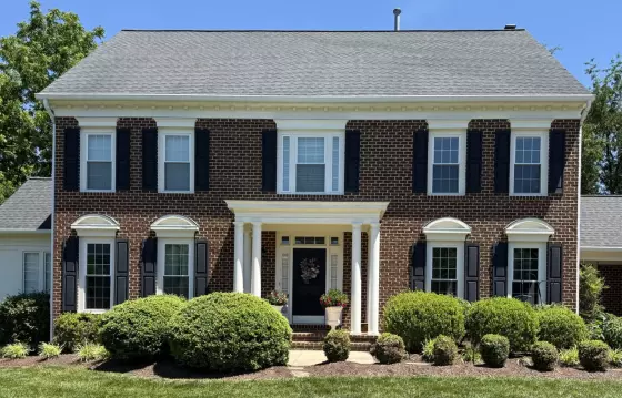 Brick house exterior with windows, shutters, and front door