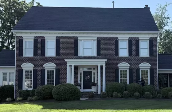 Front view of a brick house with windows, shutters, and a main entrance