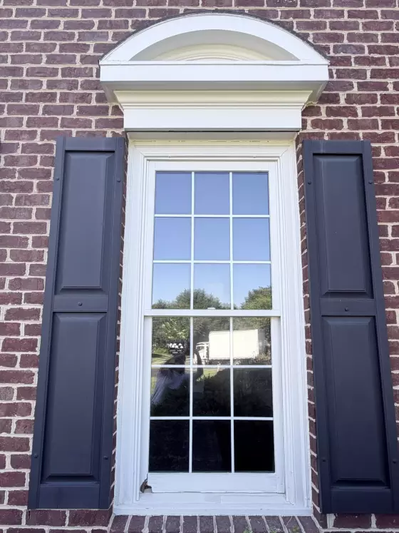 Exterior window with visible rot on lower sash and brick facade