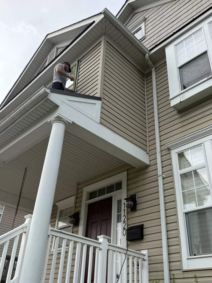 Person measuring second story window on house exterior
