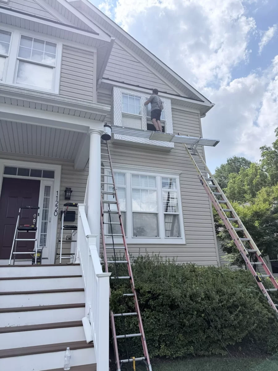 Worker on scaffolding installing or repairing window on house exterior