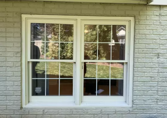Before replacement showing the original double-hung windows with grids on a brick home in Rockville, MD.
