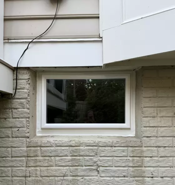 Completed basement picture window replacement with clean white trim and weather-sealed installation in Rockville, MD.