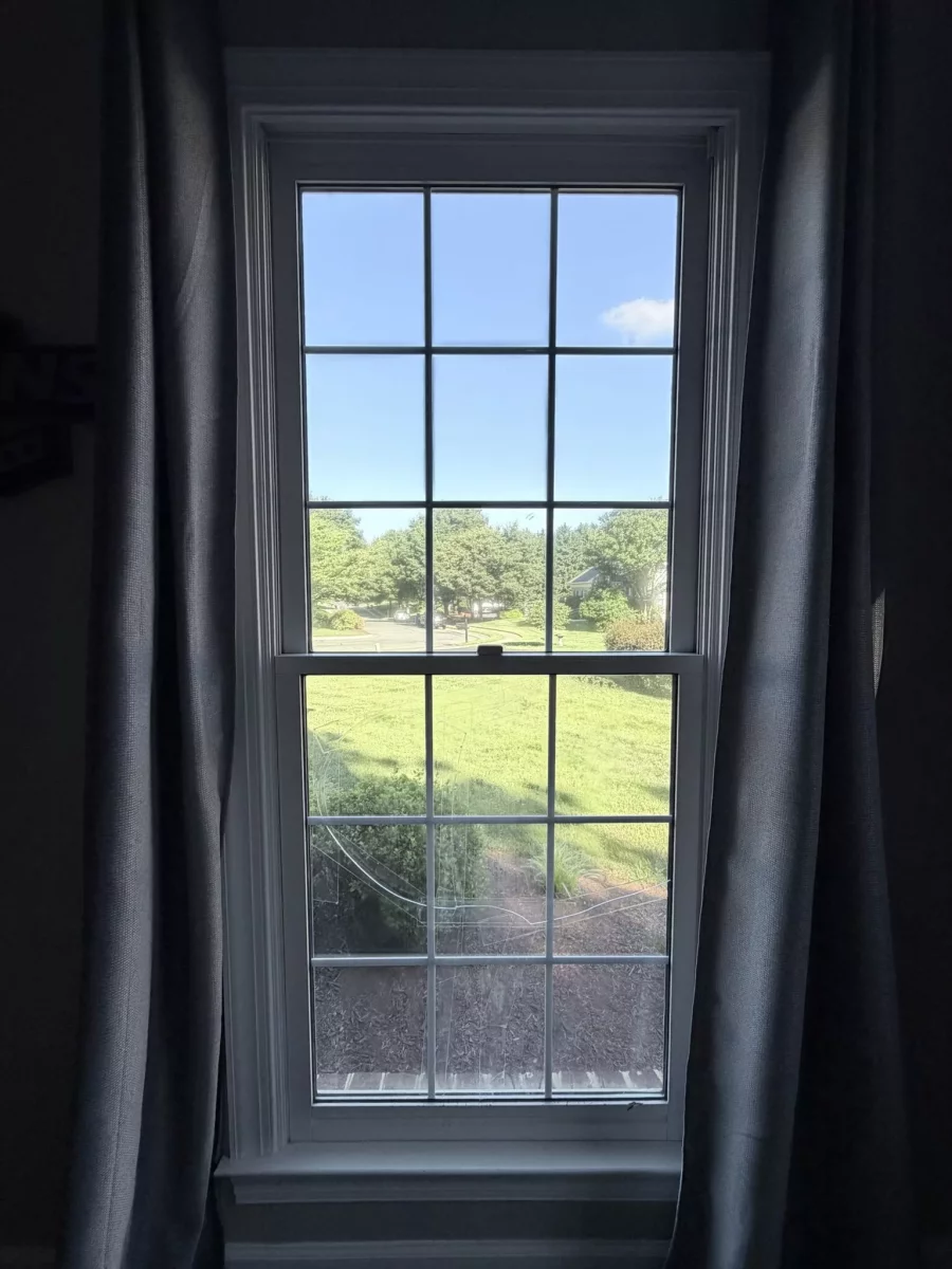 Residential window with cracked glass and curtains visible from inside