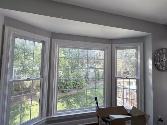 Interior view of a bay window with white trim and a cardboard box in the foreground.