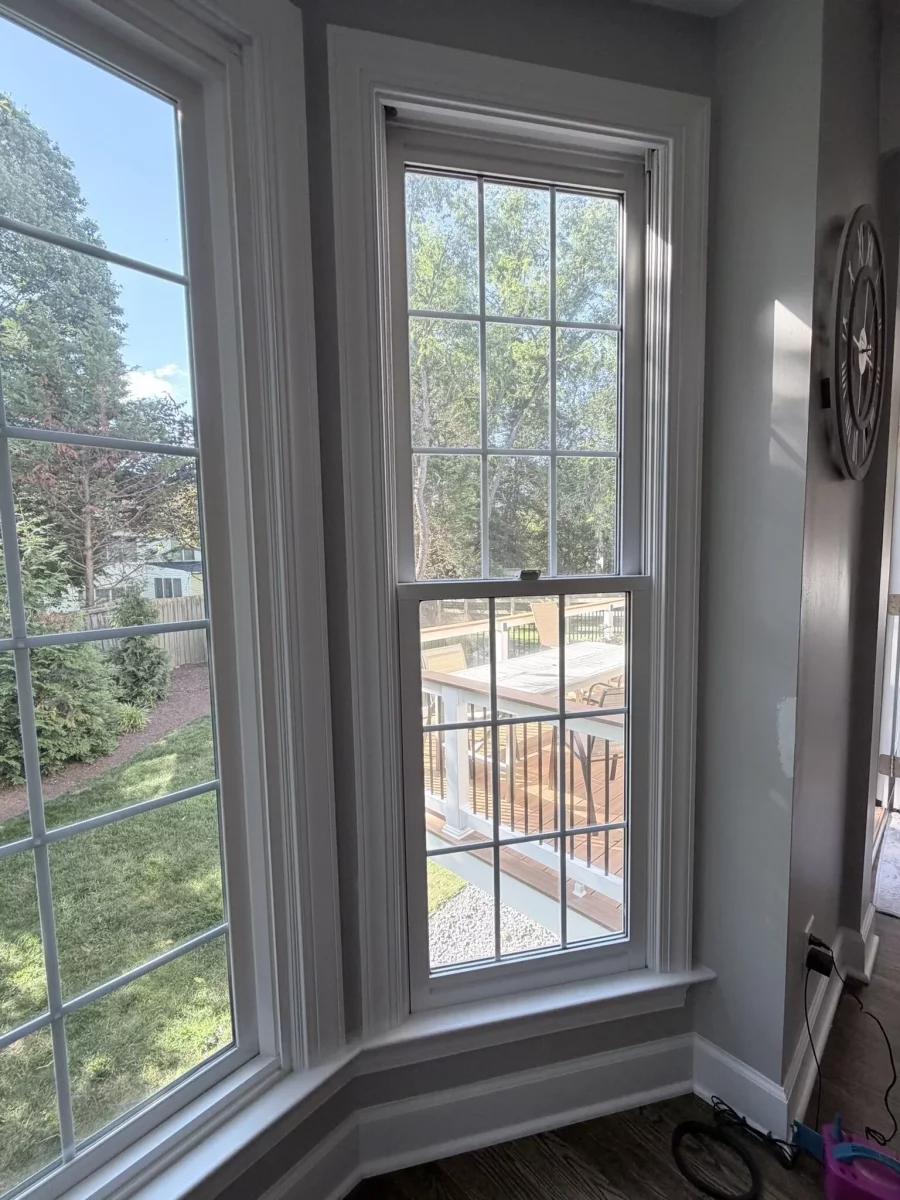 Interior view of double-hung windows with white trim overlooking backyard