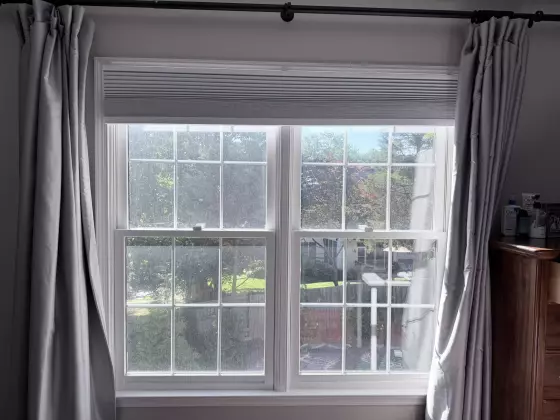 Double-hung window with white trim and curtains in a residential interior