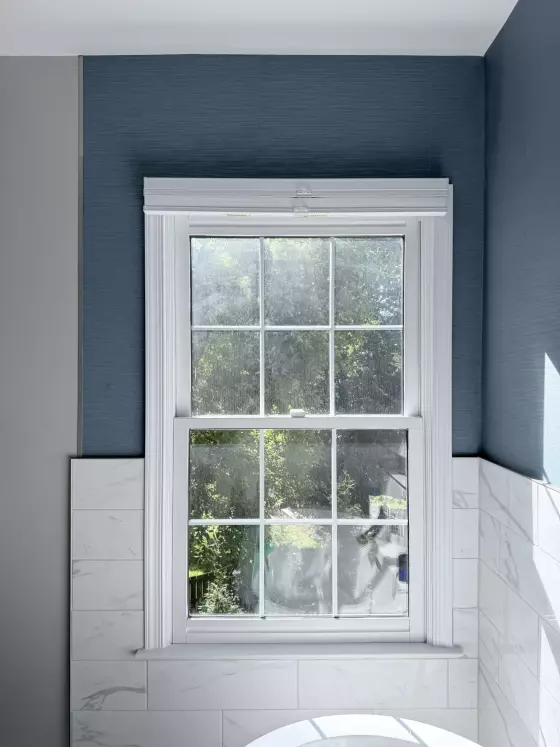 Double-hung window with white trim and tile wall in a residential interior