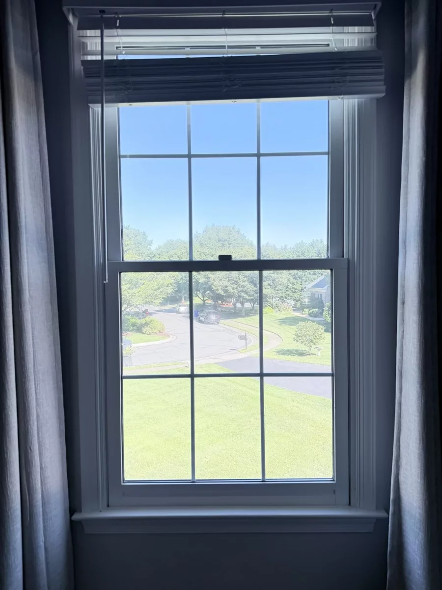 Interior view of a double-hung window with white trim and blinds