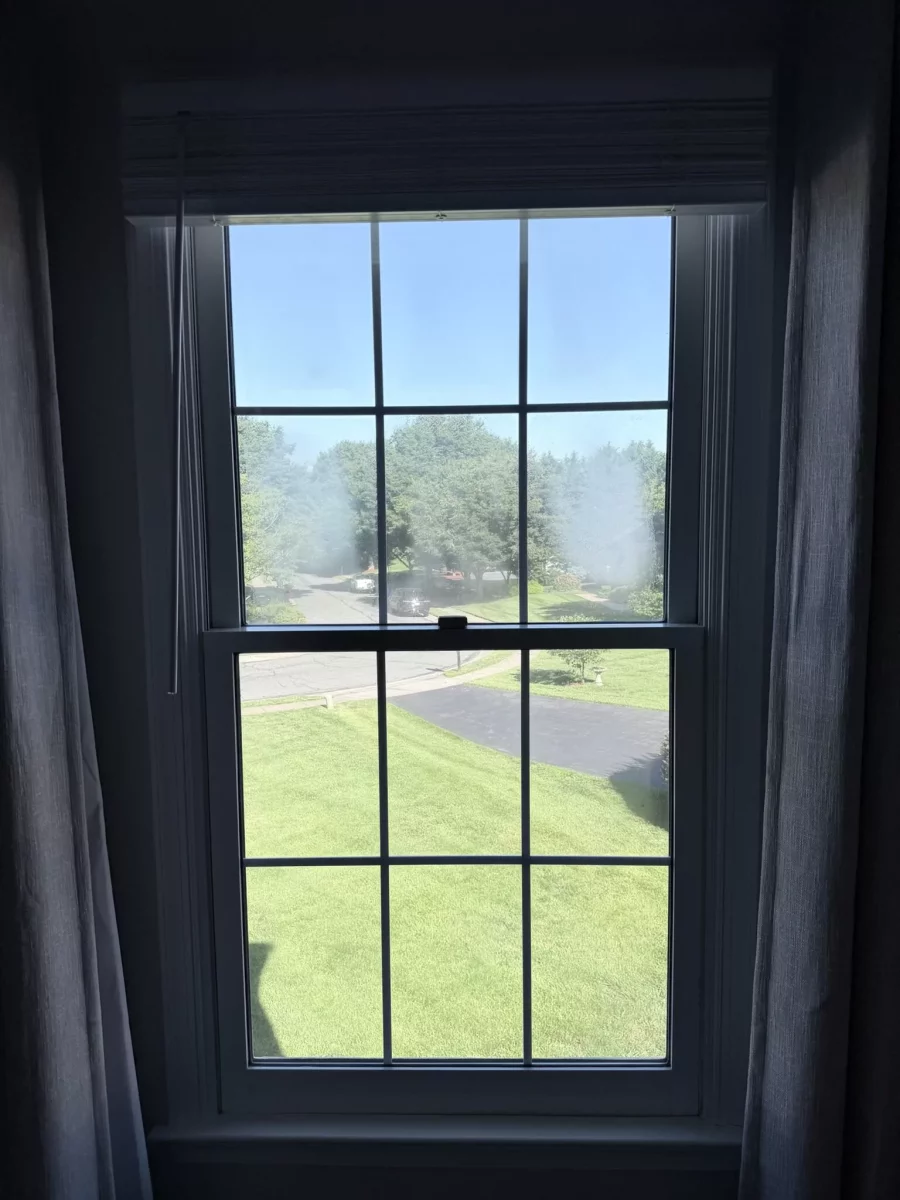 Interior view of a window with fogged glass and exterior lawn visible