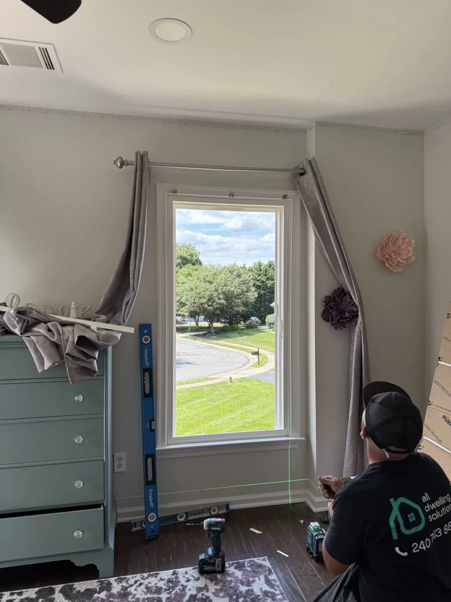 Worker installing window with tools and level in residential room
