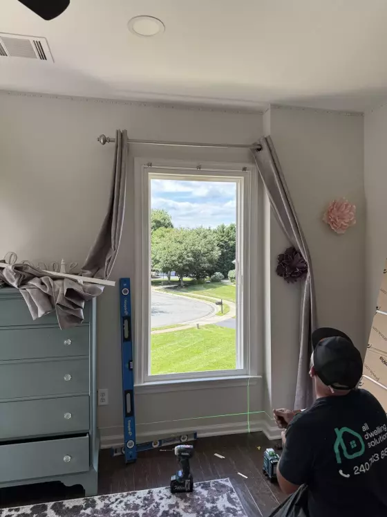 Worker installing window with tools and level in residential room