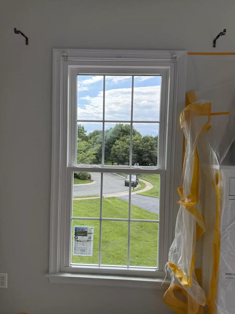 Double-hung window installation in progress with protective film and trim visible.