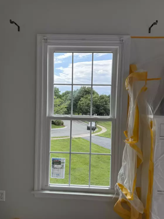 Double-hung window installation in progress with protective film and trim visible.