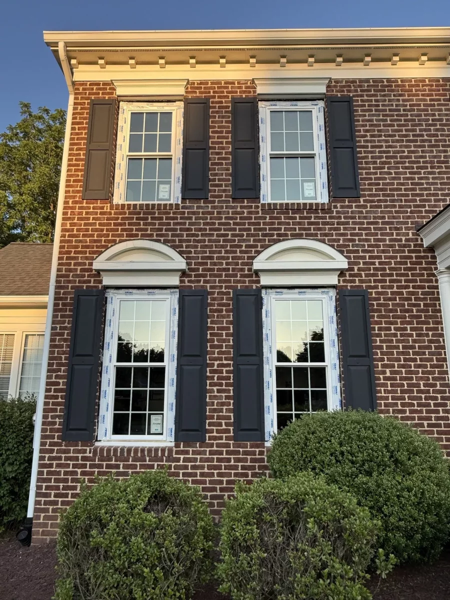 Four windows with protective film on a brick house exterior