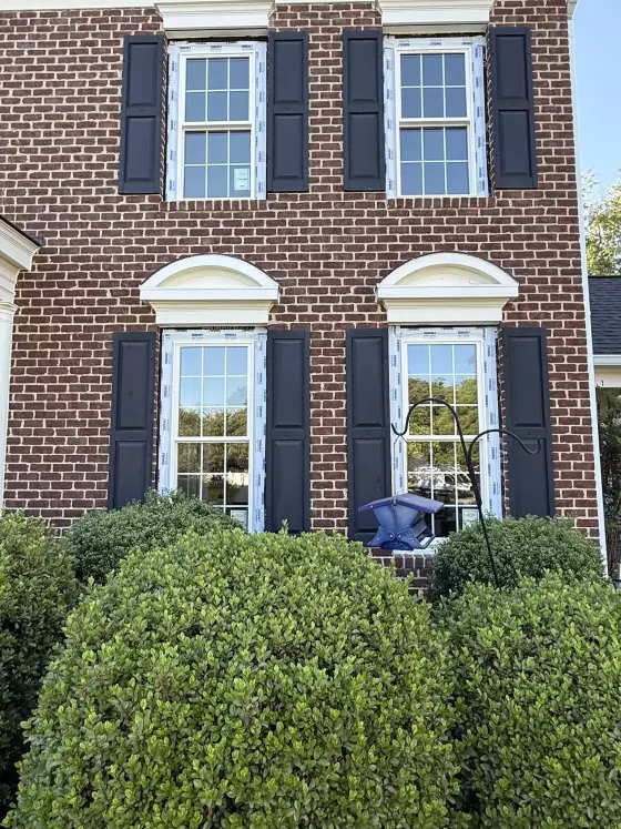 Four new windows with protective film on a brick house exterior