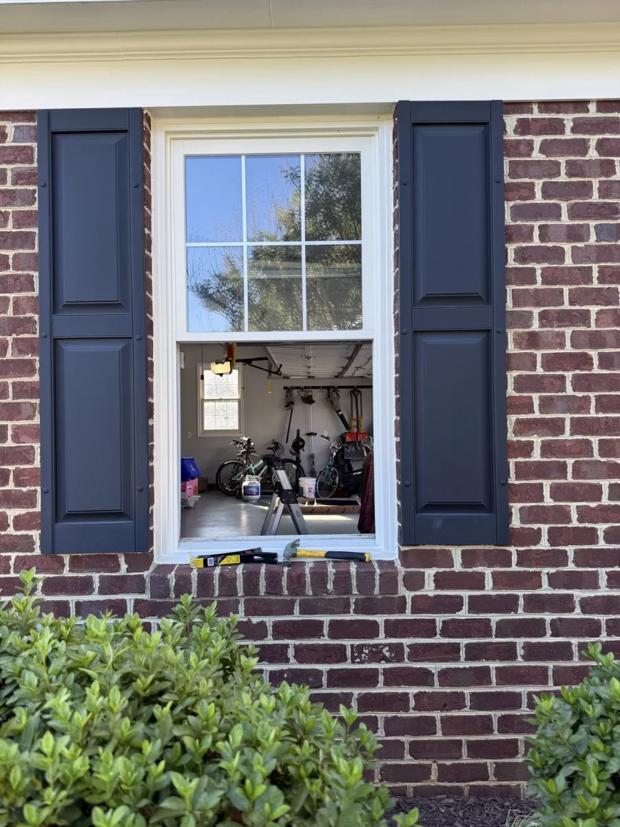 Window opening in brick wall with tools on sill and garage visible inside
