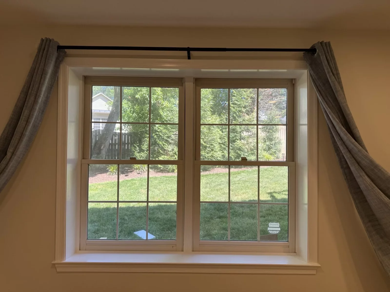 Before replacement showing the original double-hung windows with grids on a brick home in Rockville, MD.