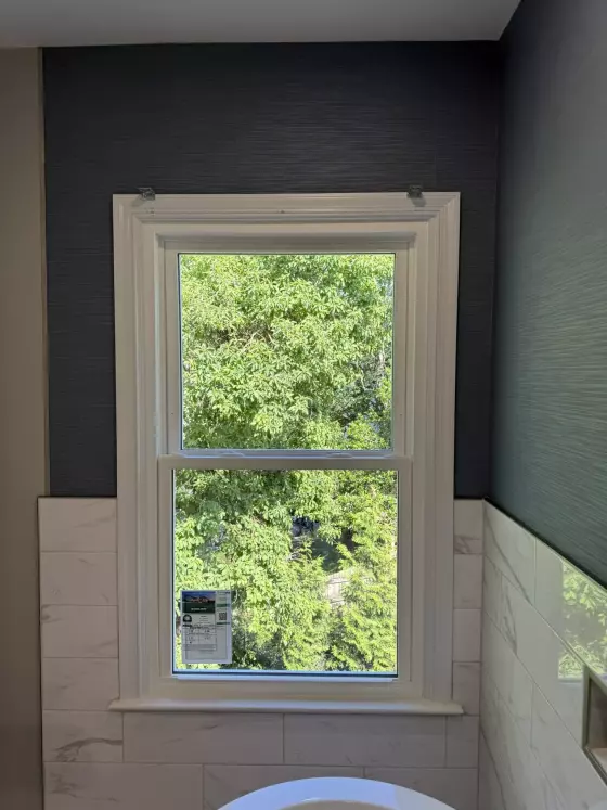Newly installed window with white frame and tile wall in bathroom