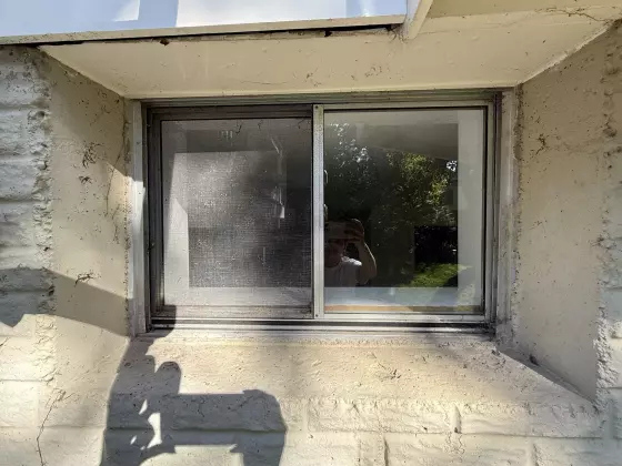 Old basement sliding window before replacement during a whole-home window upgrade in Rockville, MD.