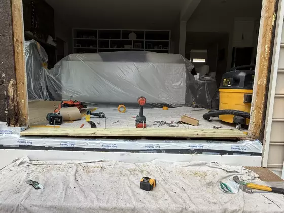 Door frame installation in progress with tools and protective coverings visible