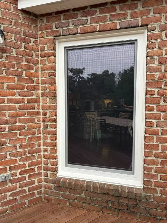 Exterior view of a single window with white trim set in a brick wall