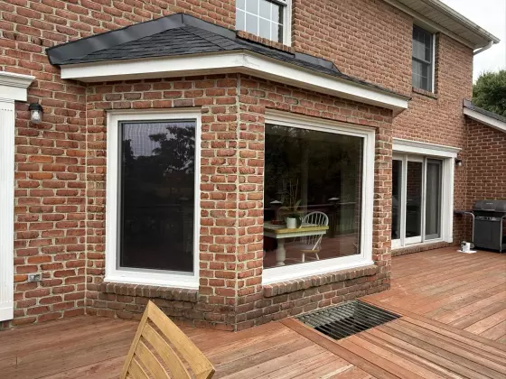 Brick house exterior with large windows and wood deck