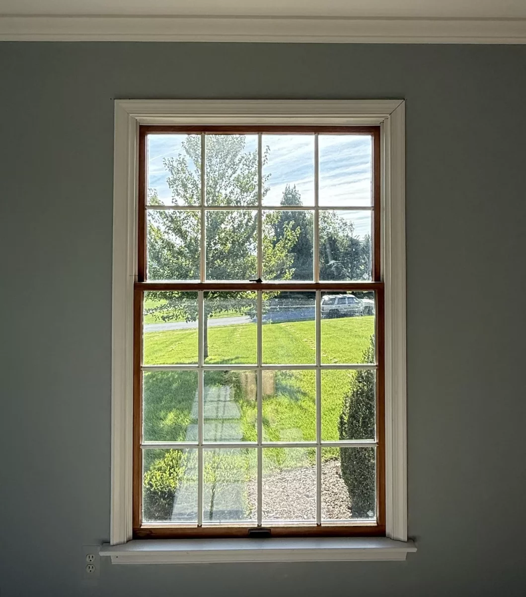 Single window with grid pattern and white trim in interior wall