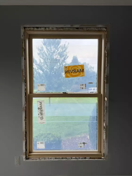 New window partially installed in interior wall with exposed frame