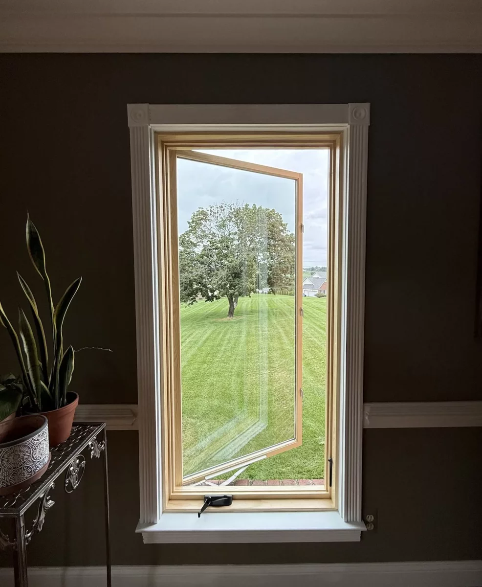 New Marvin Elevate casement window shown open after full-frame replacement with natural wood interior and finished white trim.