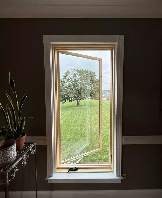 New Marvin Elevate casement window shown open after full-frame replacement with natural wood interior and finished white trim.