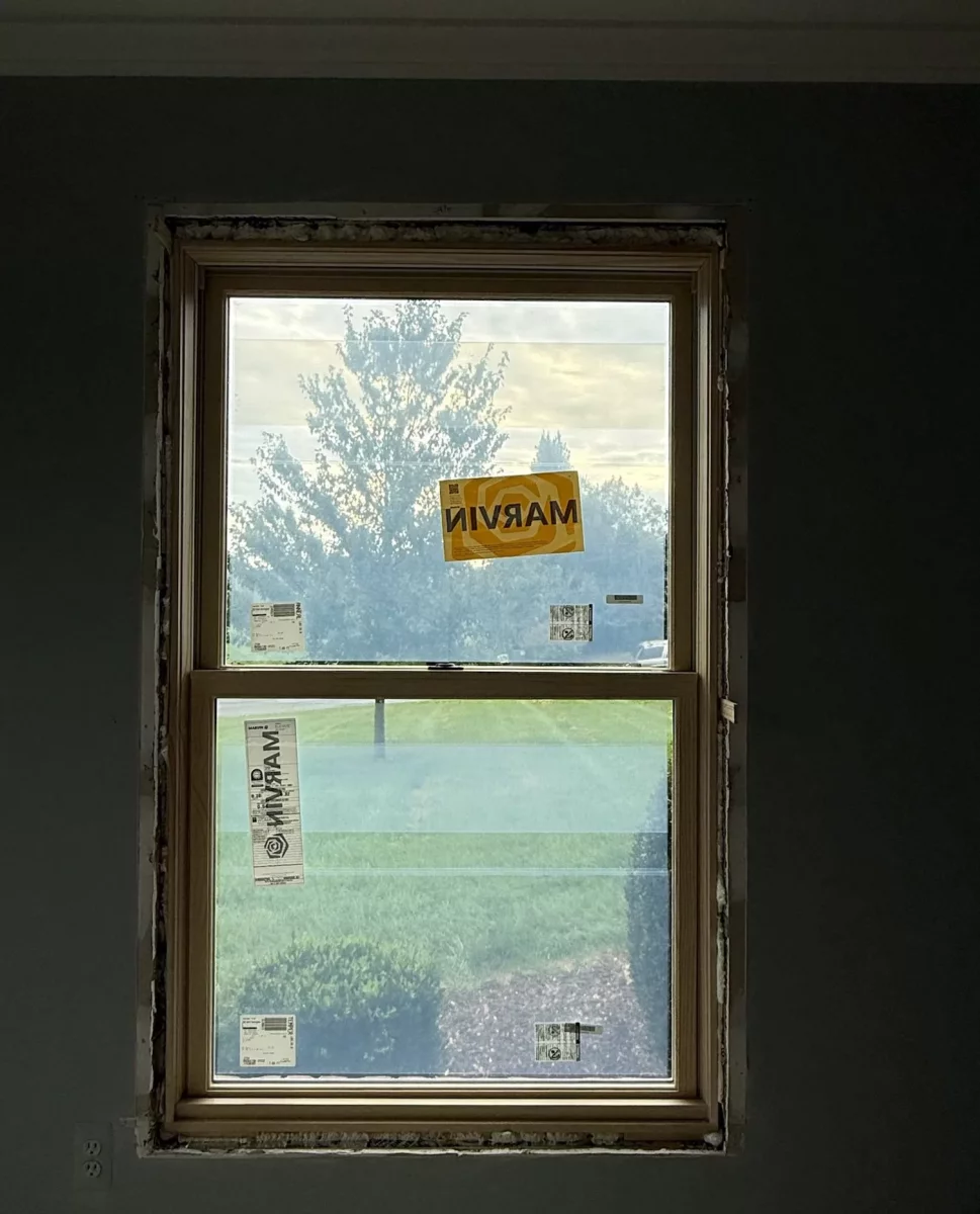 New window partially installed in interior wall with labels visible.