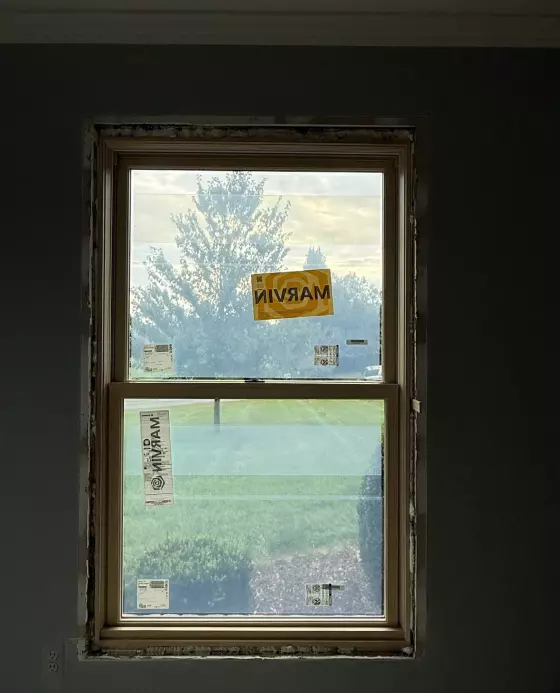 New window partially installed in interior wall with labels visible.